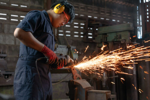 male engineer operating power tools with sparks in industrial factory